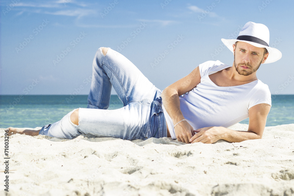 Man on beach looking to camera wearing hipster summer hat.