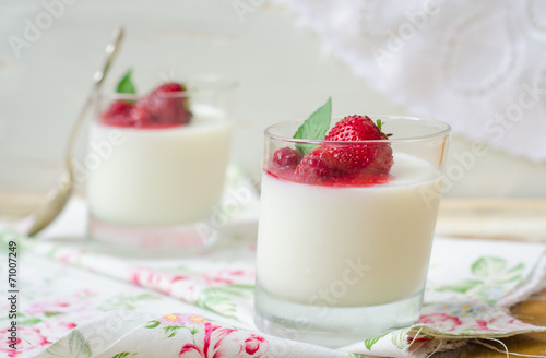 Dessert panna cotta with fresh strawberry and berries sauce in glasses on wooden background