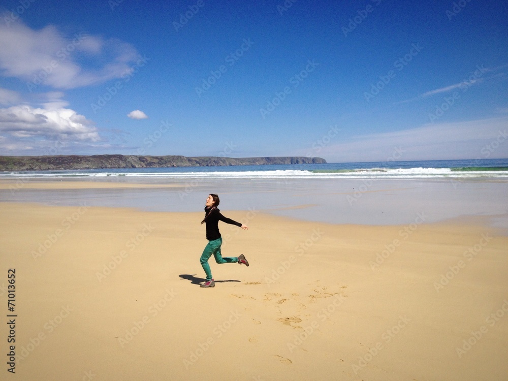 Young woman running on an empty beach in a sunny day Young woman running on an empty beach in a sunny day