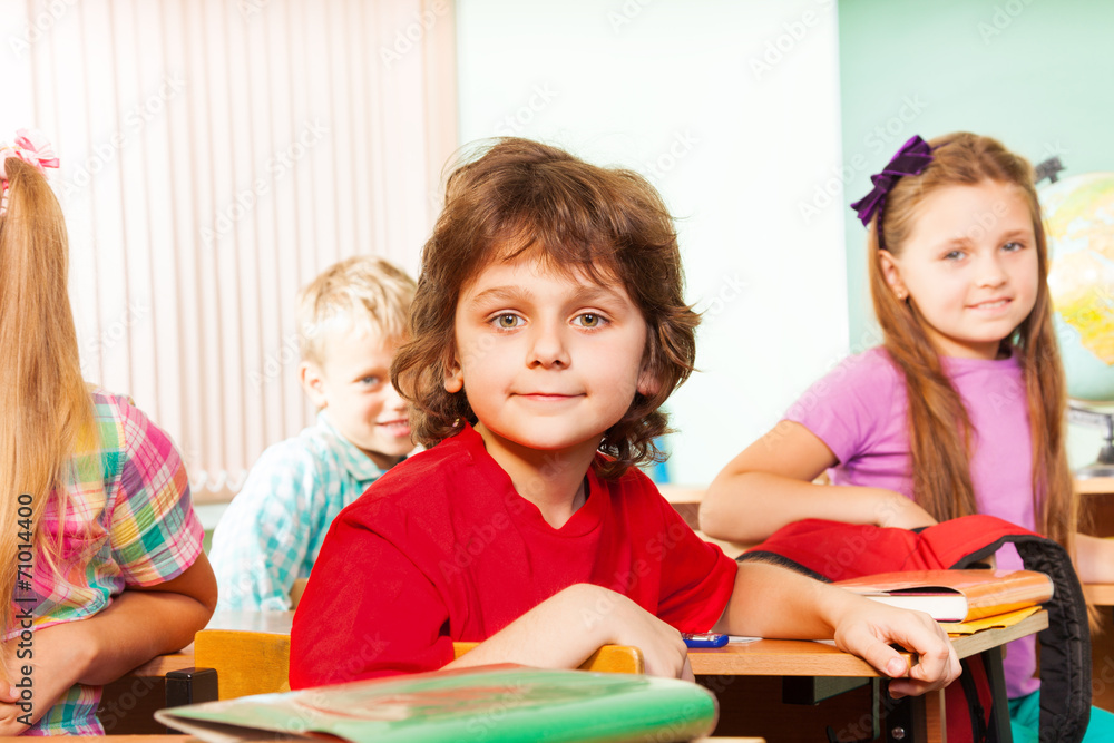 Boys with one girl look straight and sit at desks Boys with one girl look straight and sit at desks