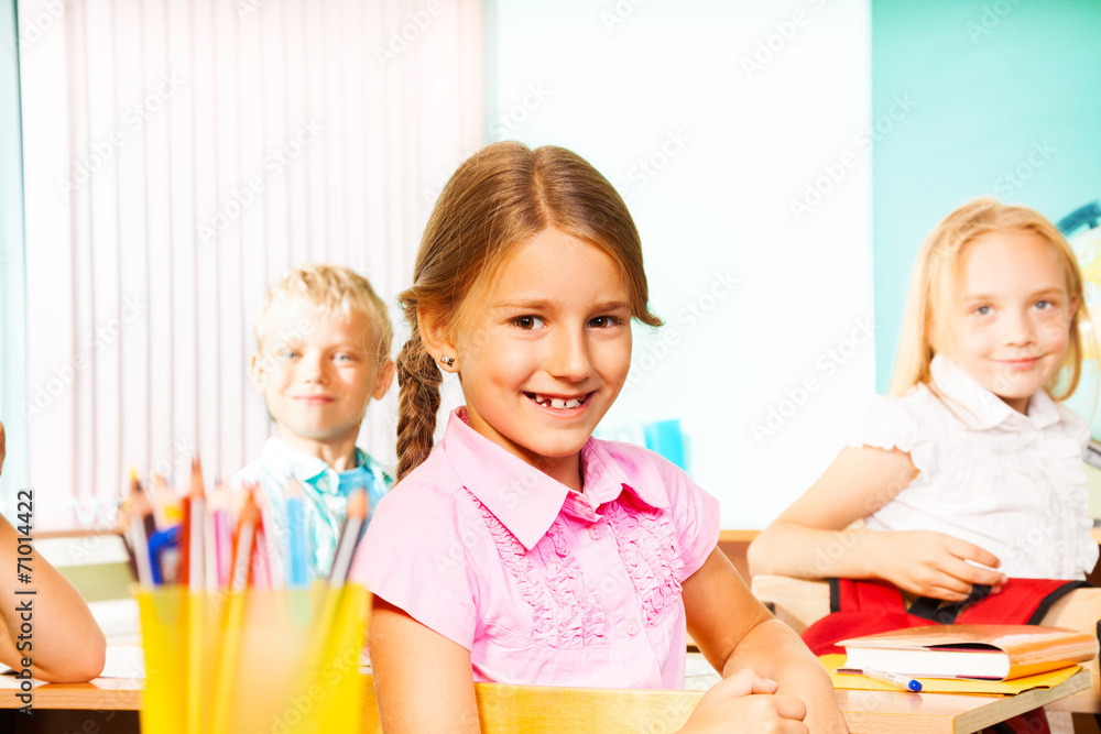 Fototapeta premium School girl and other pupils sitting at desks