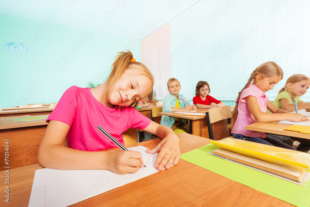 Smiling kids writing in classroom during lesson Smiling kids writing in classroom during lesson