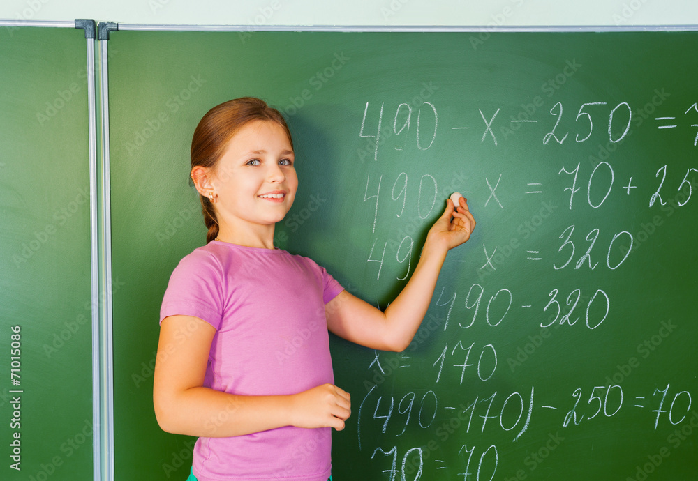 Beautiful girl with chalk in hand writes  equation