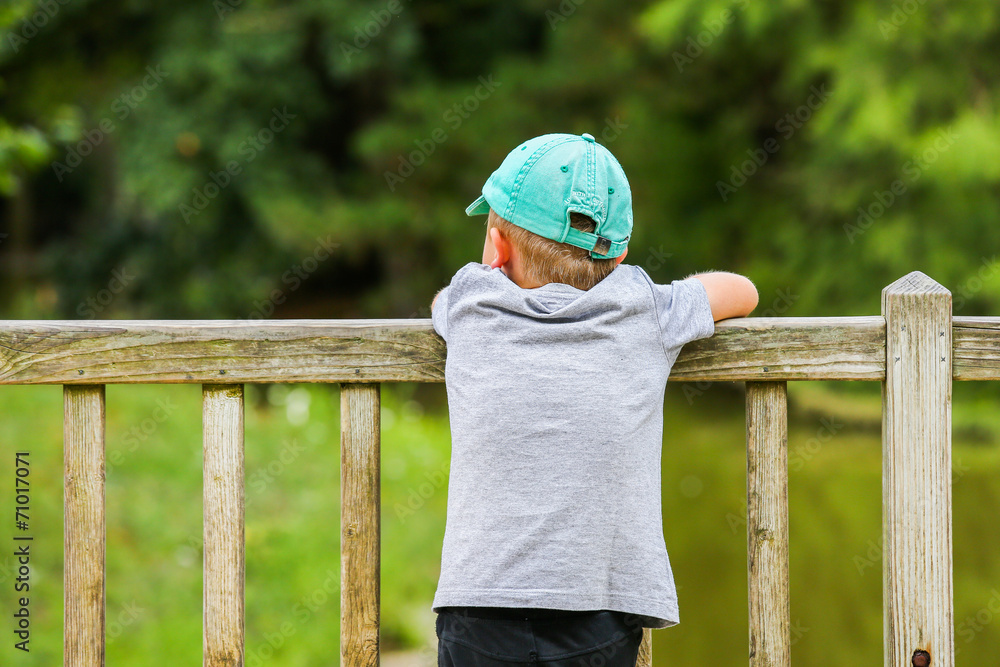 A little boy leaning over a fence A little boy leaning over a fence