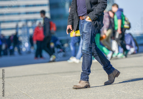 Legs of a young person walking on a busy street