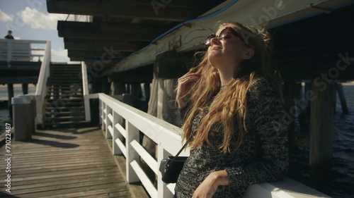 Young woman with sunglasses standing on pier by the sea