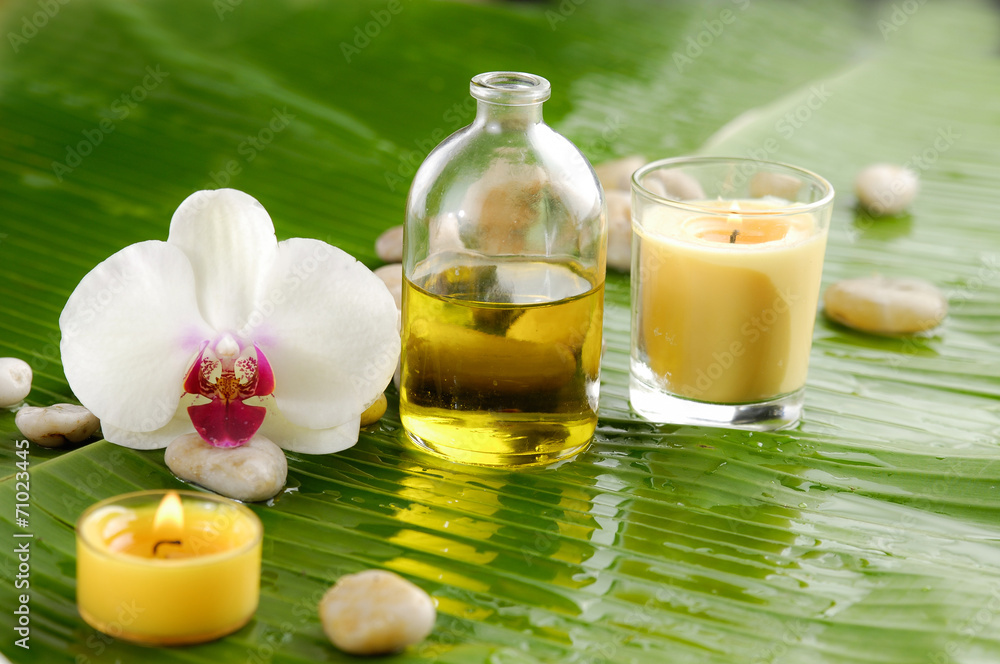 Set of white orchid and stones, candle, oil on wet banana leaf Set of white orchid and stones, candle, oil on wet banana leaf