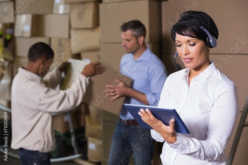 Pretty warehouse manager using tablet during busy period