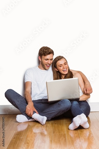 Young couple using laptop on floor