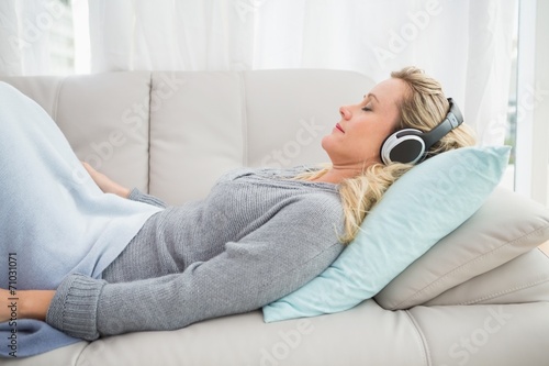 Happy girl listening to music lying on the couch