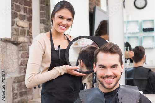 Pretty hair stylist showing man new haircut