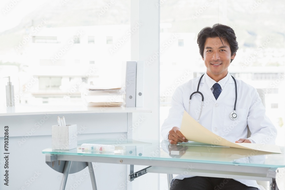 Smiling doctor sitting at his desk Smiling doctor sitting at his desk