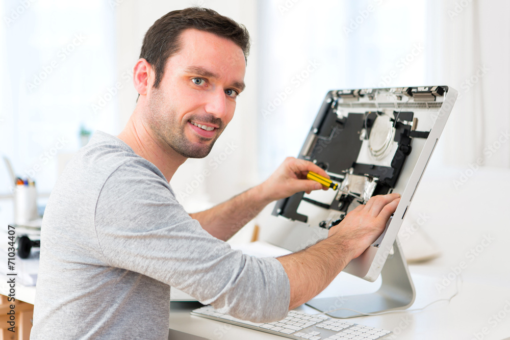 Young attractive man repairing a computer