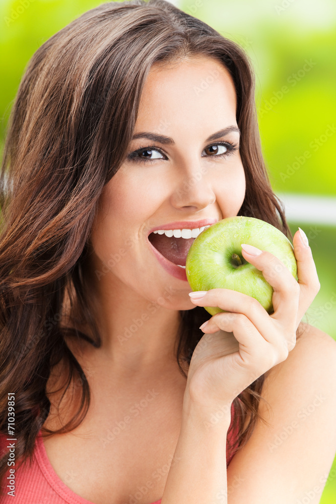 Young woman eating apple, outdoors Young woman eating apple, outdoors