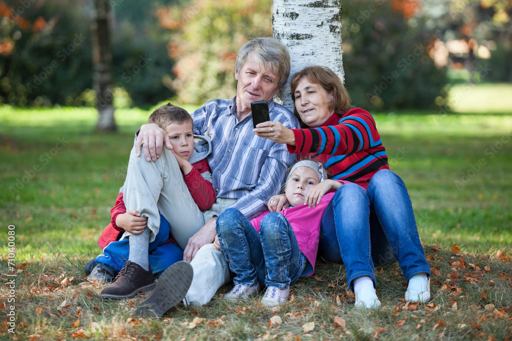 Grandparents with grandchildren together making selfie in park Grandparents with grandchildren together making selfie in park
