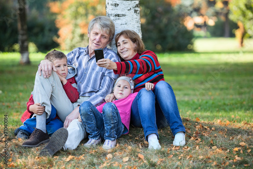 Grandparents with children sit together and make selfie phone