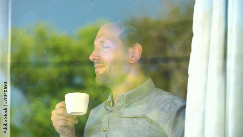 Young man enjoying morning coffee by the window Young man enjoying morning coffee by the window