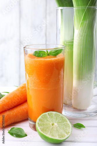 Glass of fresh carrot juice, spring onion, lime, tuft of grass