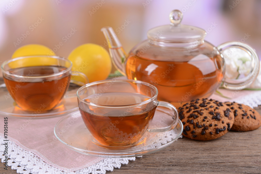 Teapot and cups of tea on table on light background Teapot and cups of tea on table on light background