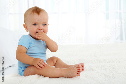 Cute baby boy on bed in room
