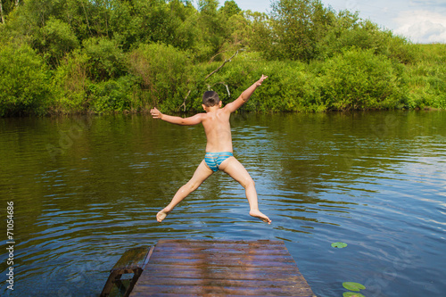 Preschool boy jumping into the river