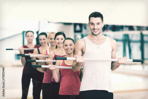 group of smiling people working out with barbells