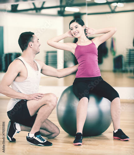 male trainer with woman doing crunches on the ball