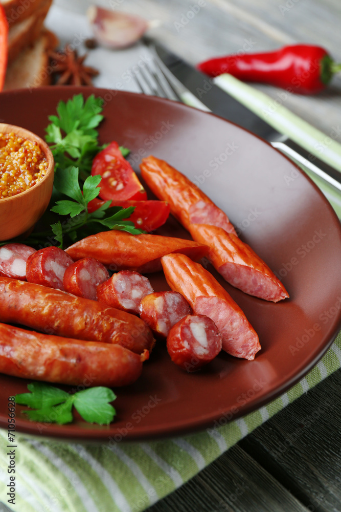 Assortment of tasty thin sausages on plate on wooden background Assortment of tasty thin sausages on plate on wooden background