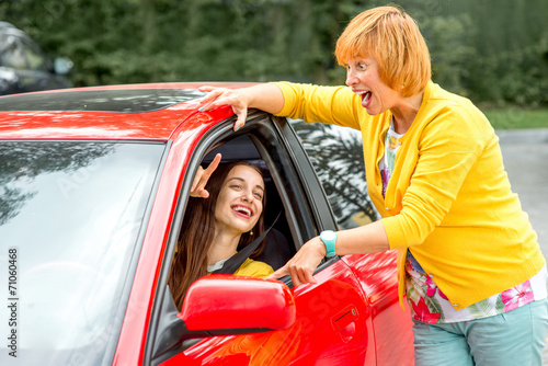 Mother with her daughter near red car