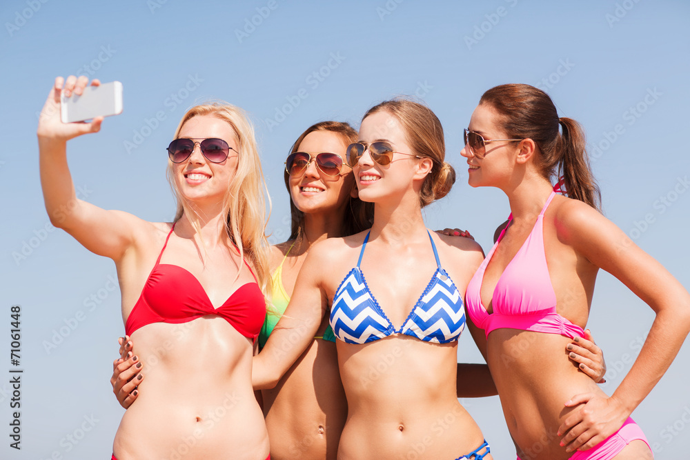 group of smiling women making selfie on beach