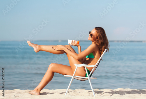 smiling young woman sunbathing in lounge on beach