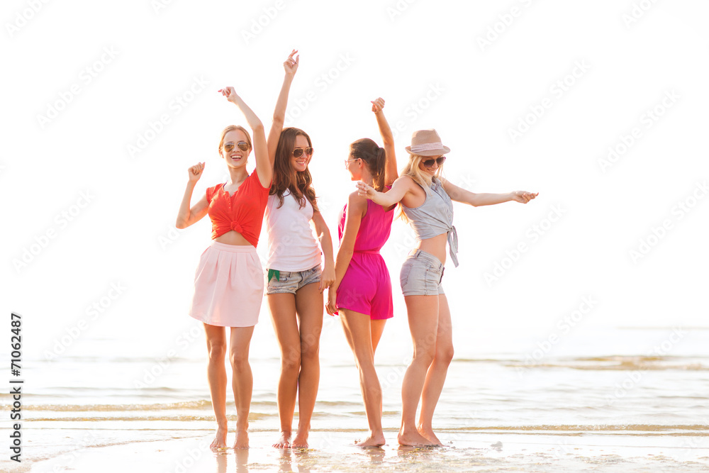 group of smiling women dancing on beach