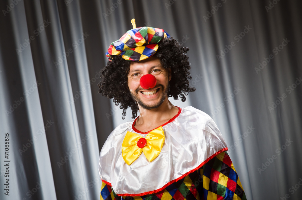 Funny clown in humorous concept against curtain Funny clown in humorous concept against curtain