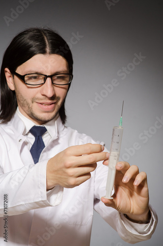 Young doctor man with  syringe against grey background