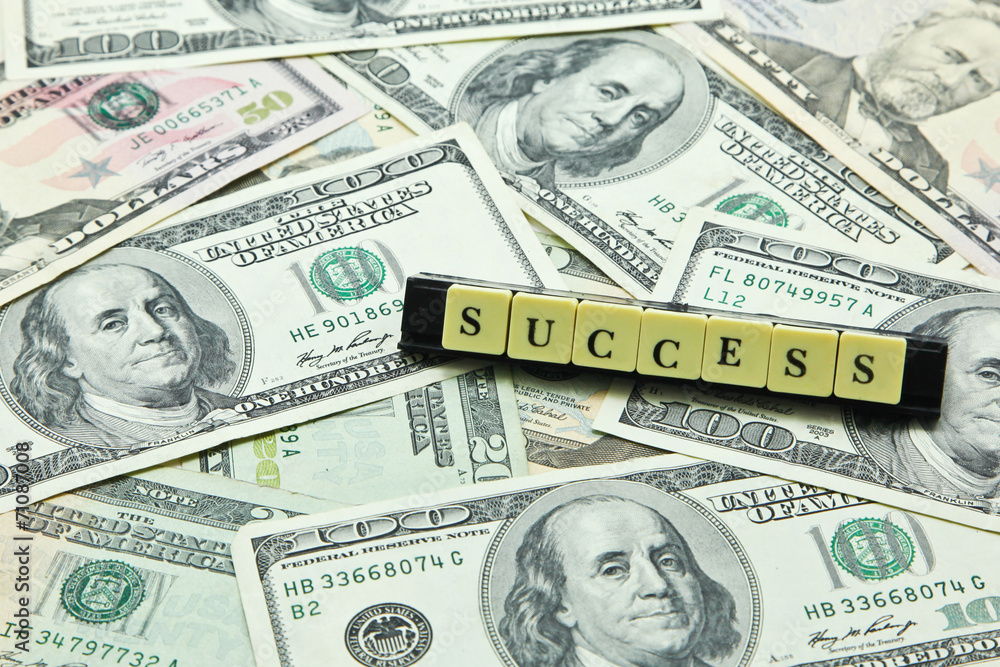 Word success on pile of US dollar banknotes Word success on pile of US dollar banknotes