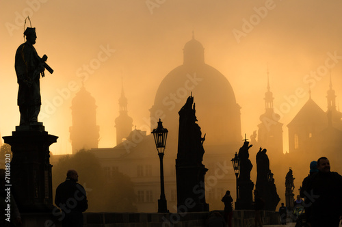 Silhouette of statue and tourists on Charles bridge during sunri