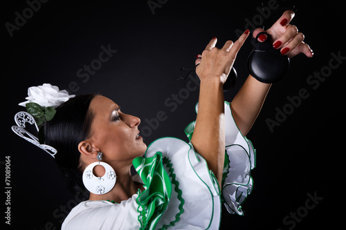 Young flamenco dancer in beautiful dress on black background.