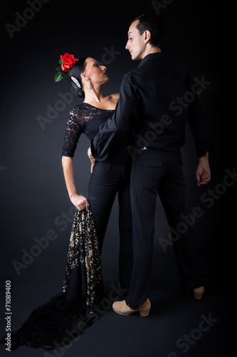 Young flamenco dancers in beautiful dress on black background.