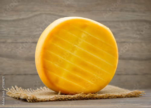Smoked cheese wheel on wooden table