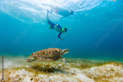 Family snorkeling with sea turtle