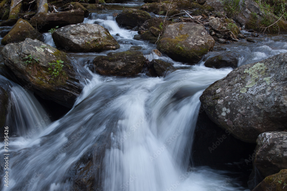 Mountain stream cascading by rocks