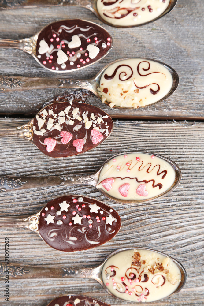 Spoons with tasty chocolate for party on old wooden table Spoons with tasty chocolate for party on old wooden table