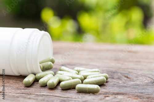 Herb capsule spilling out of a bottle