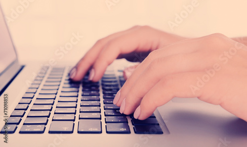Female hands working on laptop on light background