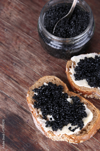 Slices of bread with butter and black caviar and glass jar of