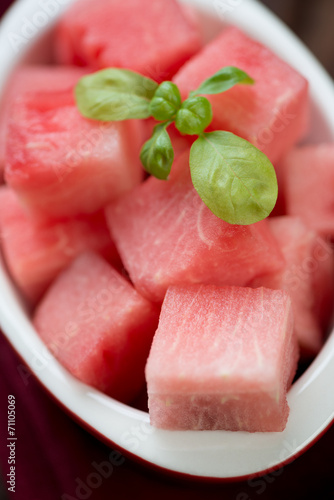 Watermelon cubes with green basil, close-up, vertical shot