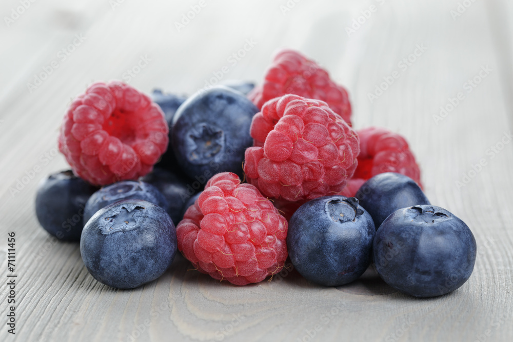 raspberries and blueberries on wood table raspberries and blueberries on wood table
