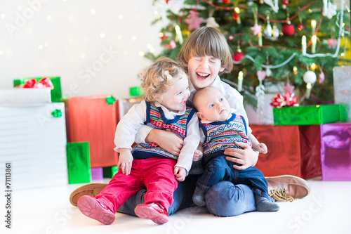 Three happy children under decorated Christmas tree