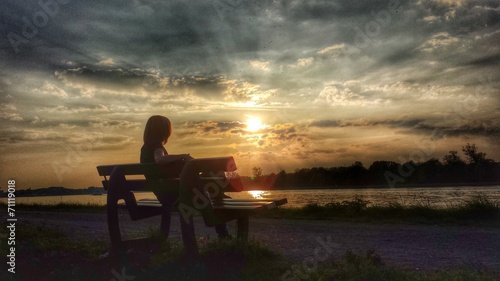 Eine Frau sitzt auf einer Bank und genießt den Sonnenuntergang