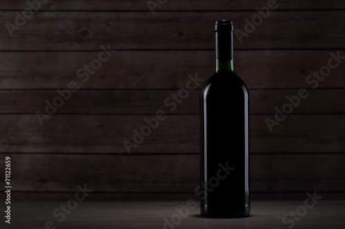 Bottle with red wine on the wooden table